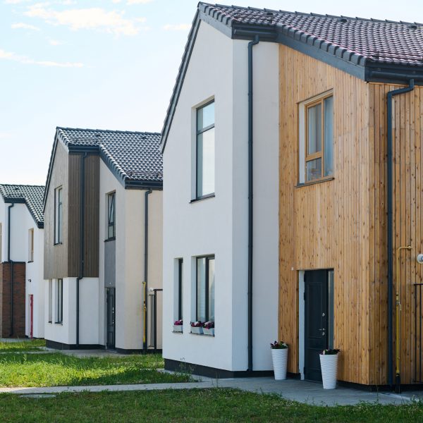Perspective of several small two storey houses standing in front of green lawns on summer day in nn-urban environment